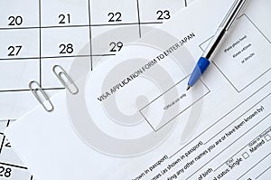 Visa application form to enter Japan and blue pen on paper calendar page