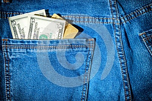 Visa card with dollar cash in blue jeans pocket
