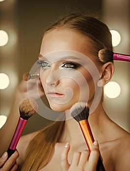 Visage course, professional make up. Woman getting powder on skin with brushes, makeup. Hands apply makeup on model face