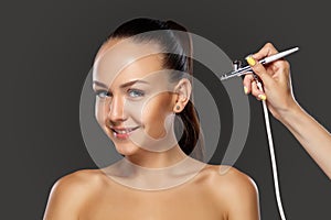 Visagist making makeup for model with aerograph photo