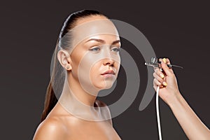 Visagist making makeup for model with aerograph photo