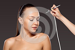 Visagist making makeup for model with aerograph photo
