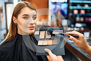 Visagiste and lady chooses cosmetic in makeup shop