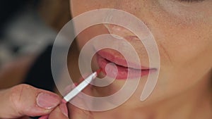 Visagiste using brush for application lipstick on lips makeup model. Close up application lip gloss. Makeup artist doing
