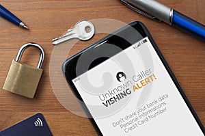 Vishing voice phishing concept, a smartphone on a table show an unknown caller call with vishing alert and a reminder to not photo
