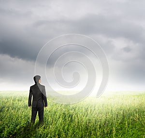 Vision business man in fields and rainclouds