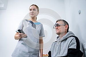 Vision correction. Selection of eyeglasses. Professional trial frames on male patient face while doctor checks eyesight