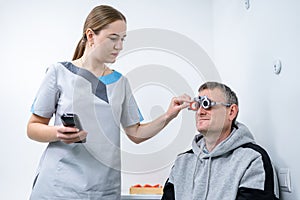 Vision correction. Selection of eyeglasses. Professional trial frames on male patient face while doctor checks eyesight