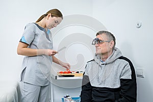 Vision correction. Selection of eyeglasses. Professional trial frames on male patient face while doctor checks eyesight