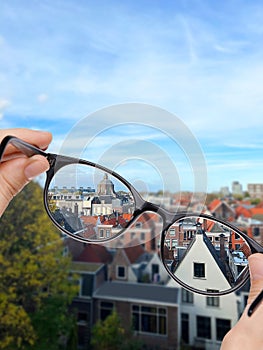 Vision correction. Woman looking through glasses and seeing cityscape clearer