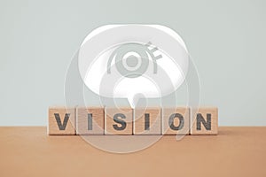 vision word on wooden cube block and eye sign inside white speech bubble for business purpose, strategy concept