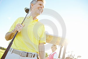 Visions of improving his handicap. Low angle shot of a handsome older golfer standing in front of a golf cart with his