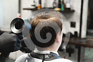 Visit to the barbershop. oung stylish man makes fashionable haircut.Barber,hairdresser,stylist blowing,drying hair with hair dryer