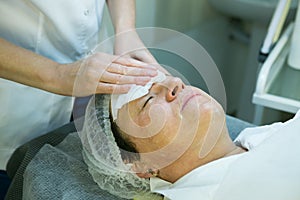 A visit to a beautician. Doctor beautician prepares the patient`s face for the procedure - carboxytherapy. The preparatory stage