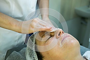 A visit to a beautician. Doctor beautician prepares the patient`s face for the procedure - carboxytherapy. The preparatory stage