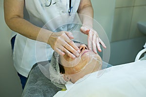 A visit to a beautician. Doctor beautician prepares the patient`s face for the procedure - carboxytherapy. The preparatory stage