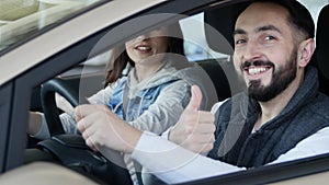 Visiting car dealership. Beautiful family is talking and smiling while sitting in their new car . young man shows finger