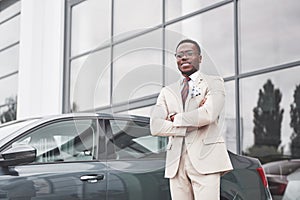 Visiting car dealership. Casual black business man in a suit near the car