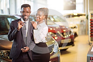 Visiting car dealership. couple holding key of their new car, looking at camera photo