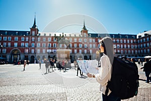 Visiting famous landmarks and places.Cheerful female traveler at famous Plaza Mayor square reading a map