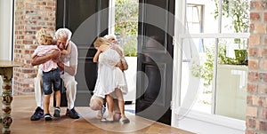 Visiting grandparents bend and kneel to hug grandchildren photo