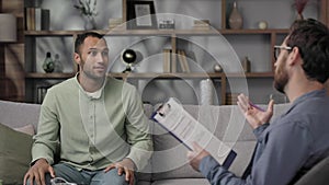 Visiting a psychologist Afro-american man is sitting on the couch and talking to a psychotherapist. He thanks the doctor