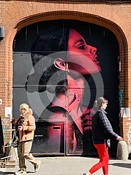 People walking past graffiti street art in Shoreditch, East London England UK