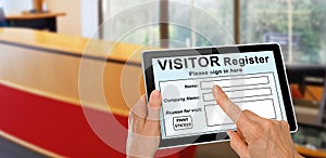 Visitor completing a sign in register form on computer tablet