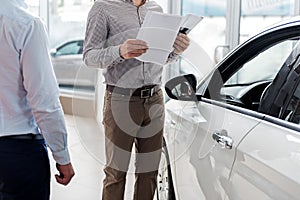 Visitor looking through agreement in car dealership