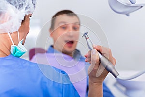 Visitor man afraid of drill sitting in chair in medical center