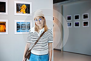 Visitor woman smiling on art gallery collection in front framed paintings pictures