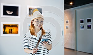 Visitor woman standing takes picture art gallery collection in front framed paintings pictures