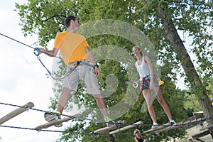 Visitors in adventure park clambering with ropes