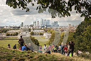 Visitors enjoy the view of the Canary Wharf skyscrapers from Greenwich park in London