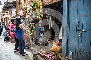 Visitors selecting and negotiating for goods along historic busy narrow street around Bhaktapur, Nepal.
