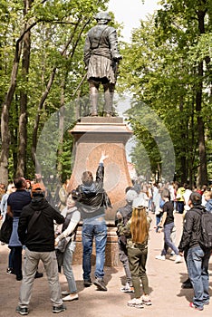 Petergof, Russia, July 2019. Visitors to the park throw coins for the tops of the boots of the statue of Peter.