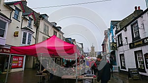 Visitors walking through a local market with traditional houses alongside in a rainy day