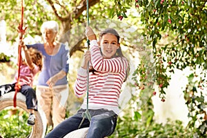 Visits with Gran are the best. Portrait of a young girl on a tire swing with her grandmother and little brother in the