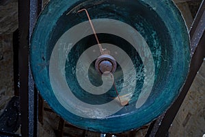 VisiÃÂ³n desde abajo y en perpendicular de una campana con badajo de bronze verde antigua restaurada en la iglesia de la Clerecia photo