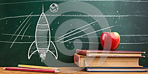 Visual arts on a blackboard books, apples, pencils, rocket drawing