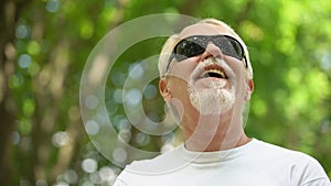 Visually impaired man in sunglasses listening nature sounds, heightened senses