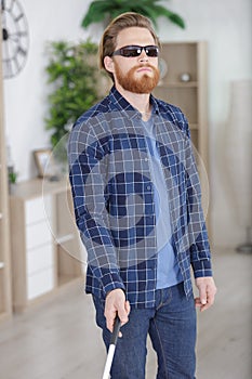 visually impaired man using stick to move around home