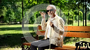 Visually impaired old man using voice control app in smartphone, innovations