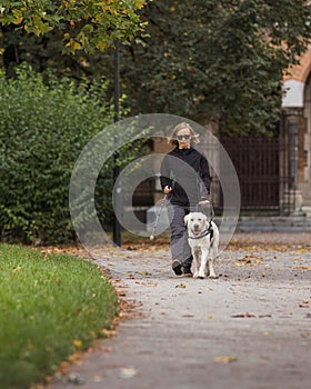 Visually impaired woman walking in park with a guide dog assistance