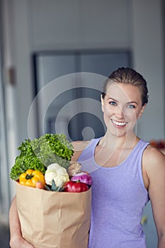 Vitality is about feeding your body with healthy foods. Portrait of a young attractive woman carrying a bag of groceries