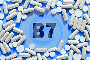 Vitamin B7 text in white capsules frame on blue background. Pill with Biotin