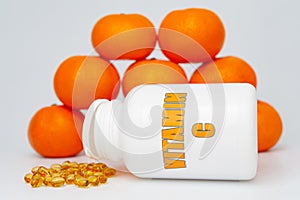 Vitamin C bottle with scattered softgel and oranges. Isolated on white background. Healthy immune system
