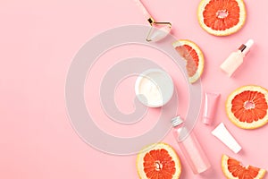 Vitamin c citrus cosmetics set with slices of grapefruit on pink background. Natural SPA beauty products concept. Flat lay, top