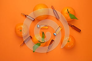 Vitamin C concept. Tangerines fruits, vitamin C in glass ampoules on a bright orange background.ampoules and Serum with Vitamin C.