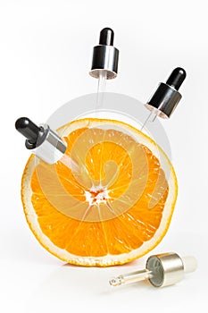 Vitamin C in the form of serum in pipettes, taken from an orange for youthful skin.